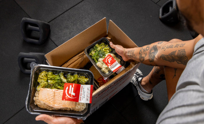 Fuel Meals container with salmon and broccoli into a gym bag, highlighting convenient and nutritious meal options.